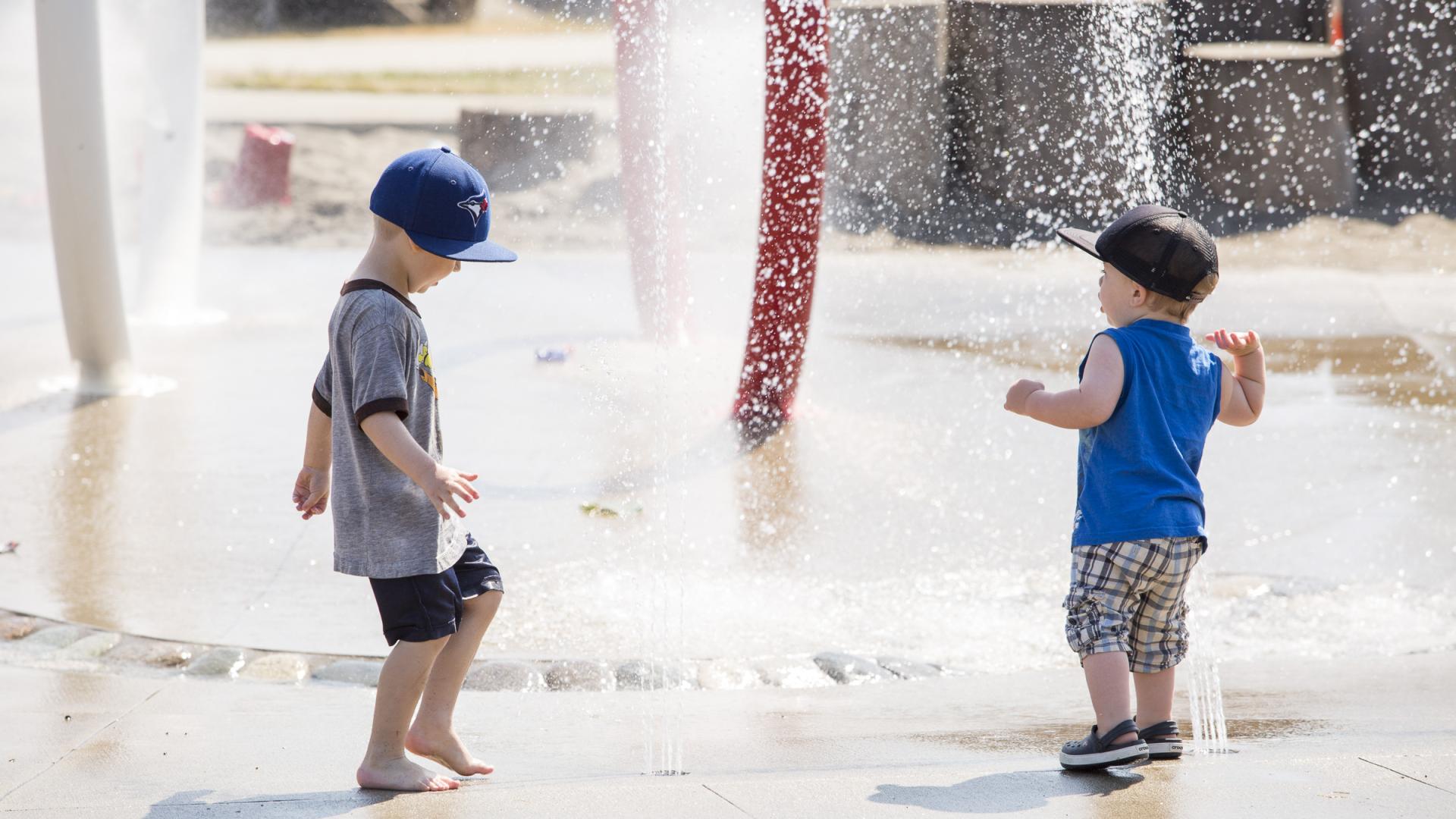 two young children playing in a spray park